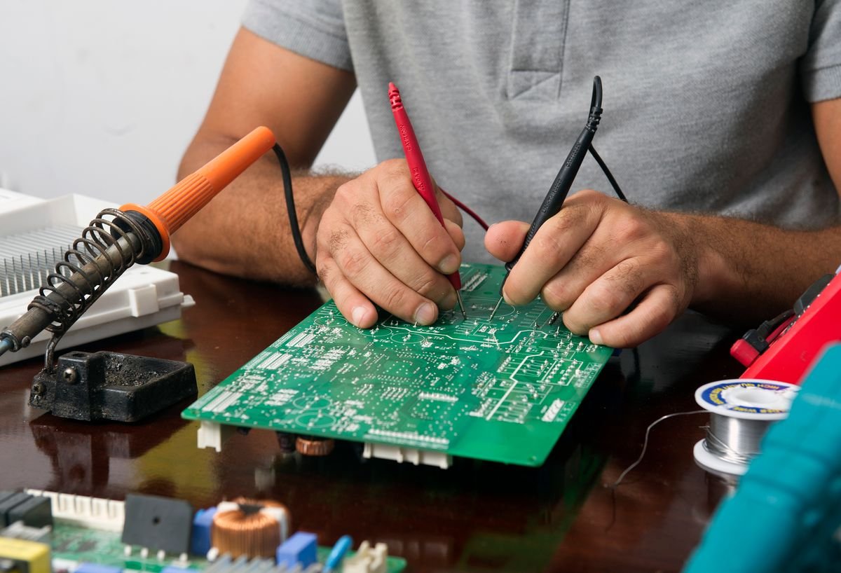 Técnico testando placa eletrônica de motor de portão automático com multímetro